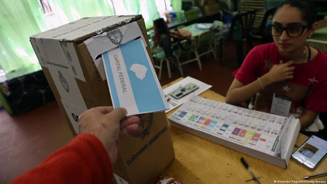 Mano coloca voto en urna electoral. Sobre la mesa se divisan las nuevas boletas.