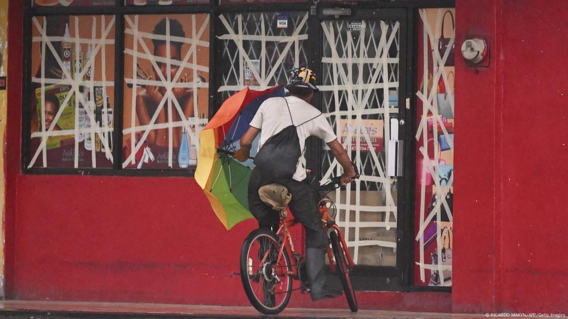 Un ciclista se apresta a buscar refugio en Portmore, Jamaica, cerca de un negocio cerrado por la llegada del huracán Melissa.