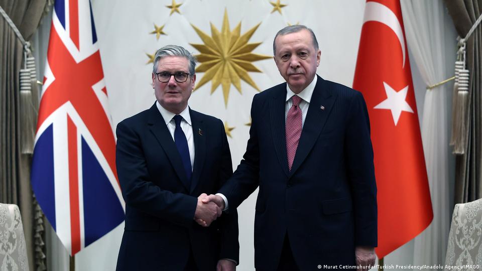 Cumhurbaşkanı Recep Tayyip Erdoğan ile İngiltere Başbakanı Keir Starmer, kendi ülke bayrakları ve Türkiye Cumhurbaşkanlığı logosu önünde tokalaşıyor