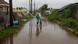 Homem caminha ao lado de bicicleta em rua alagada na Jamaica