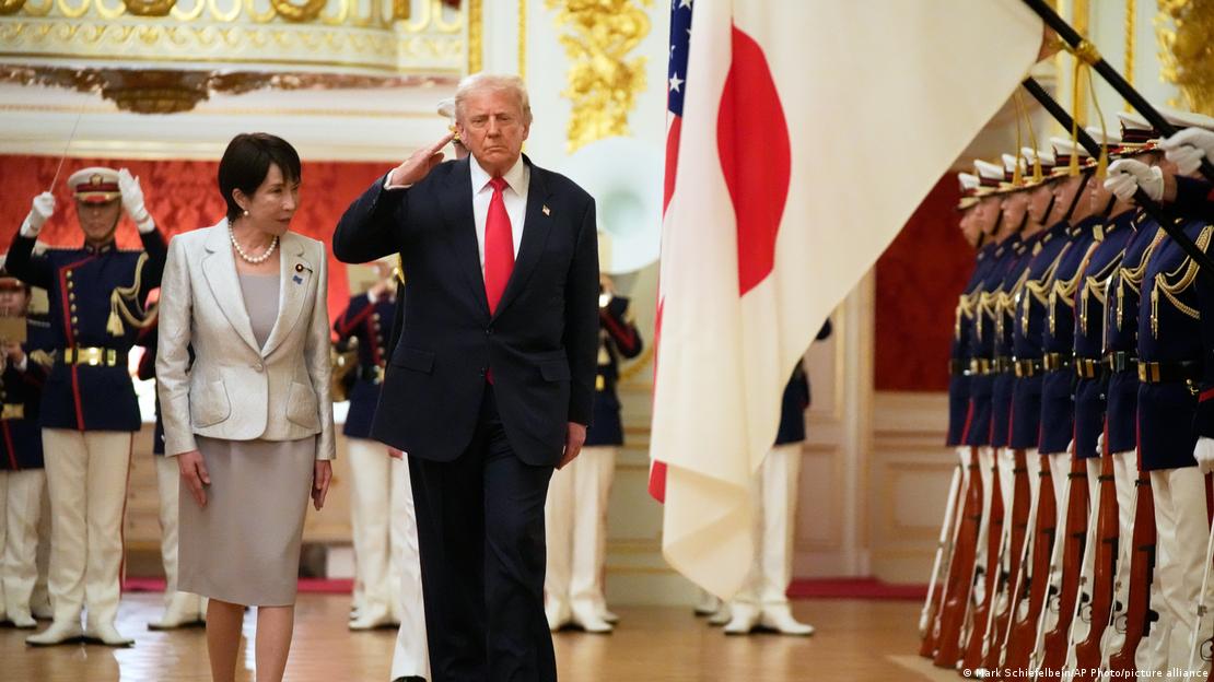 Donald Trump y Sanae Takaichi, flanqueados por soldados y con la bandera de Japón ondeando detrás.
