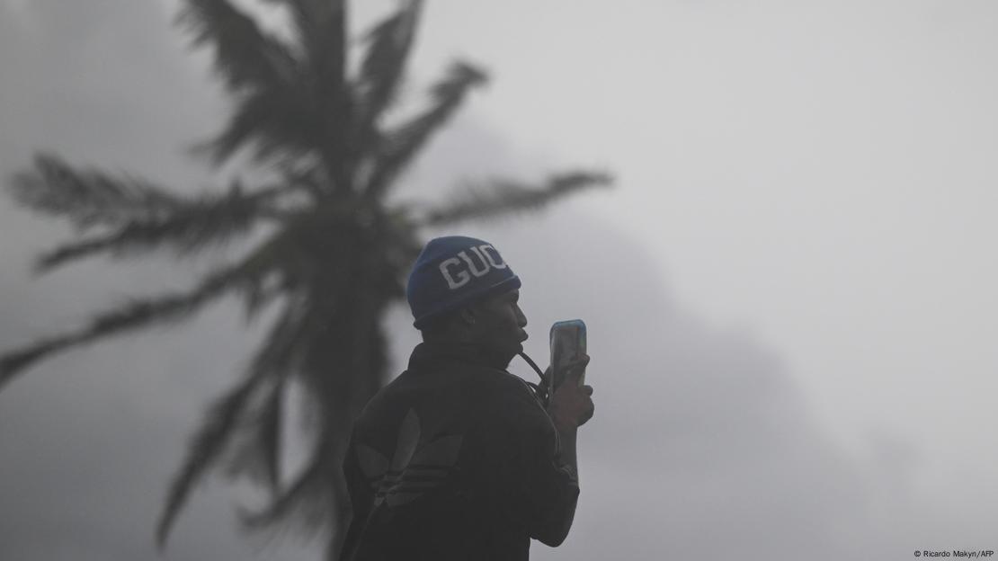 Homem ao lado de coqueiro com chuva e ventos fortes Homem ao lado de coqueiro com chuva e ventos fortes