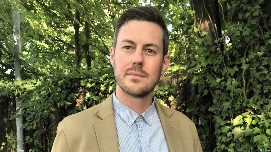 Portrait of a man wearing a light coloured jacket and shirt.
