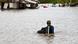 En medio de una inundación, un hombre camina con un televisor. En medio de una inundación, un hombre camina con un televisor.