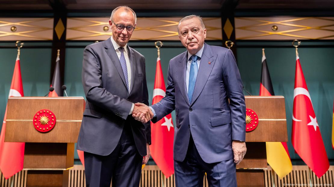 Basın toplantısının ardından tokalaşarak kameralara poz veren Merz ve Erdoğan. Arkalarında basın toplantısı için kurulan kürsülerle Türk ve Alman bayrakları var.