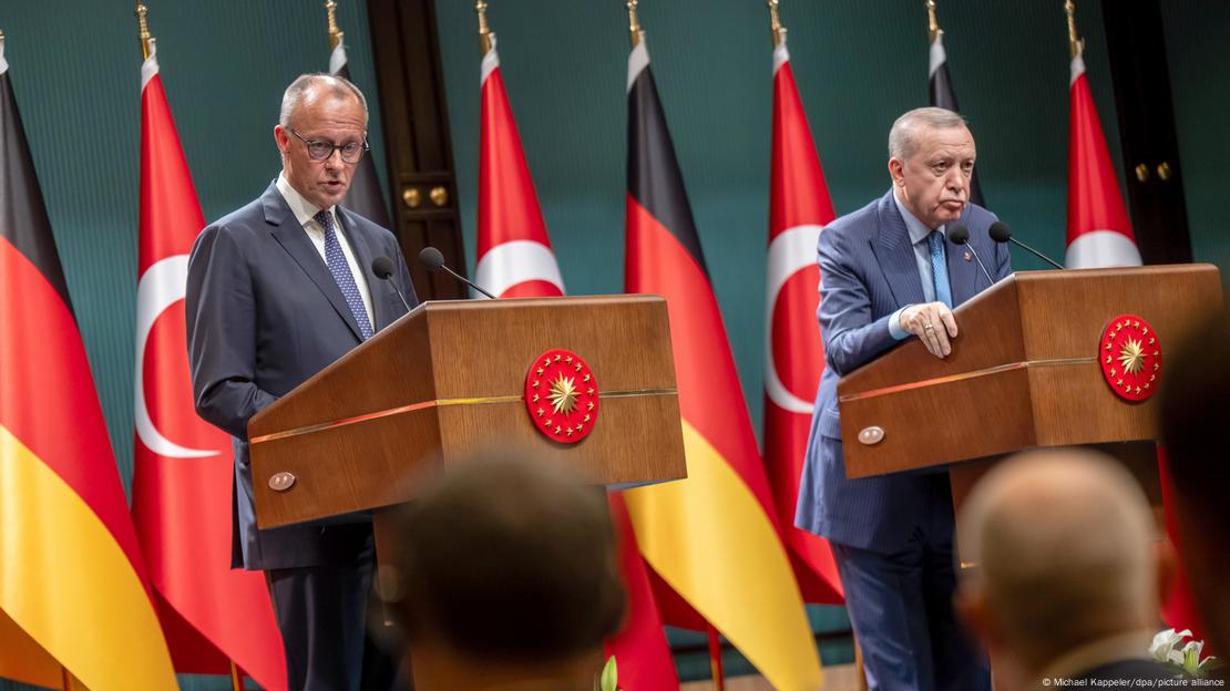 Basın toplantısı için kurulan kürsülerde konuşan Merz ve Erdoğan. Arkalarında Türk ve Alman bayrakları var.