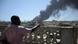 A man watches as smoke billows after a drone strike on the port of Port Sudan on May 6, 2025. A man watches as smoke billows after a drone strike on the port of Port Sudan on May 6, 2025.