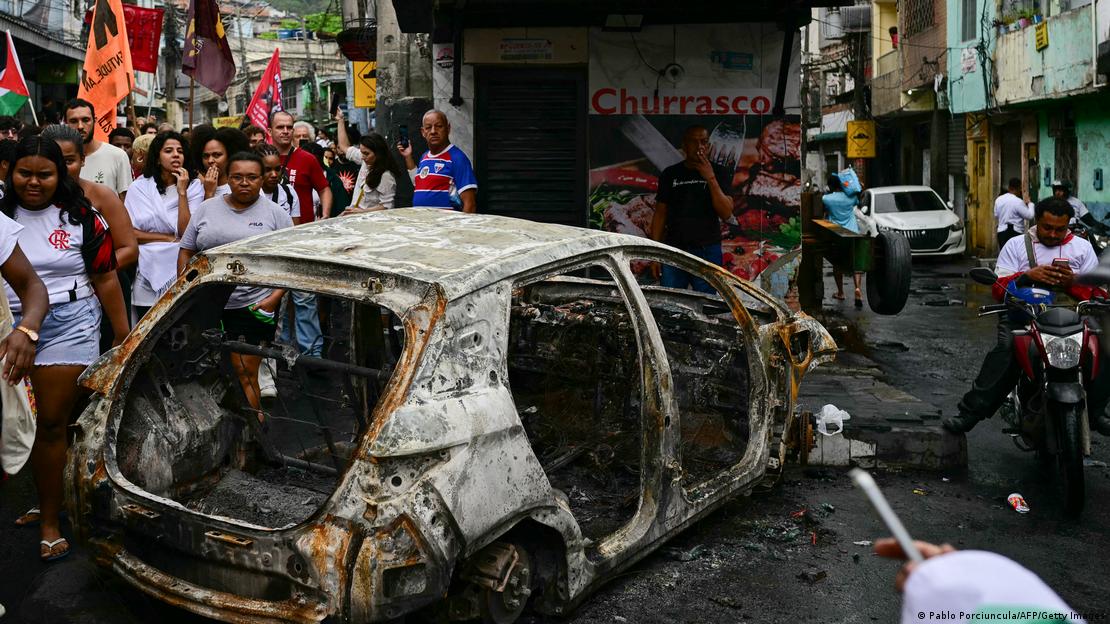 Activistas y residentes pasan junto a un vehículo quemado mientras participan en una protesta en el complejo Penha, en Río de Janeiro (31.10.2025)