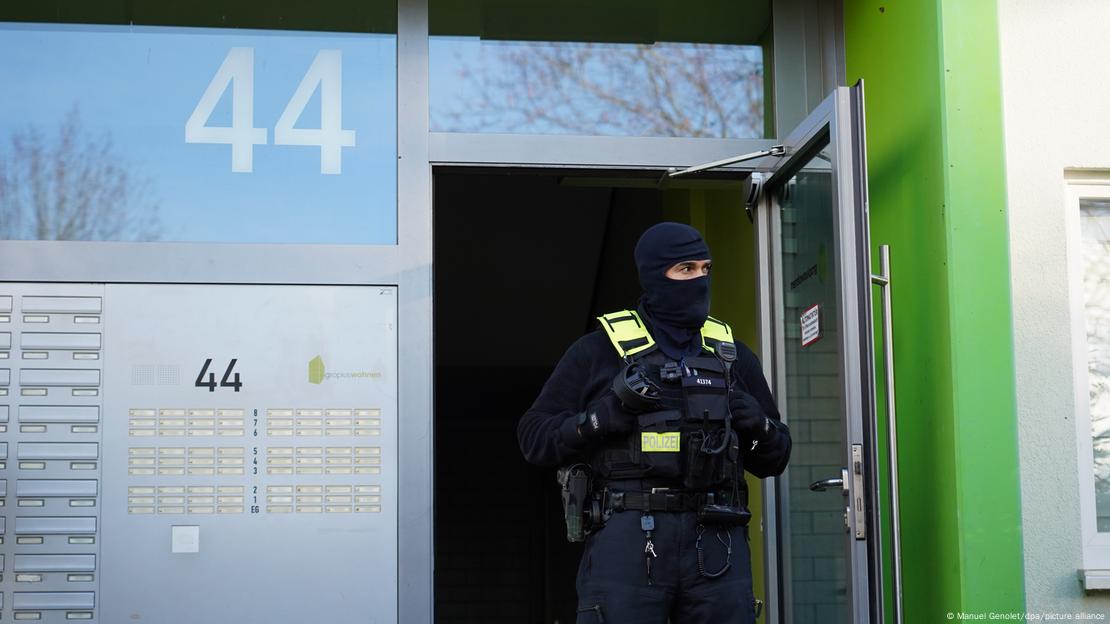 Policial com o rosto coberto sai de prédio residencial durante operação de busca em Berlim Policial com o rosto coberto sai de prédio residencial durante operação de busca em Berlim