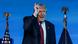 Un bărbat (Donald Trump) gesticulează, fiind încadrat de steagul şi stema SUA Un bărbat (Donald Trump) gesticulează, fiind încadrat de steagul şi stema SUA