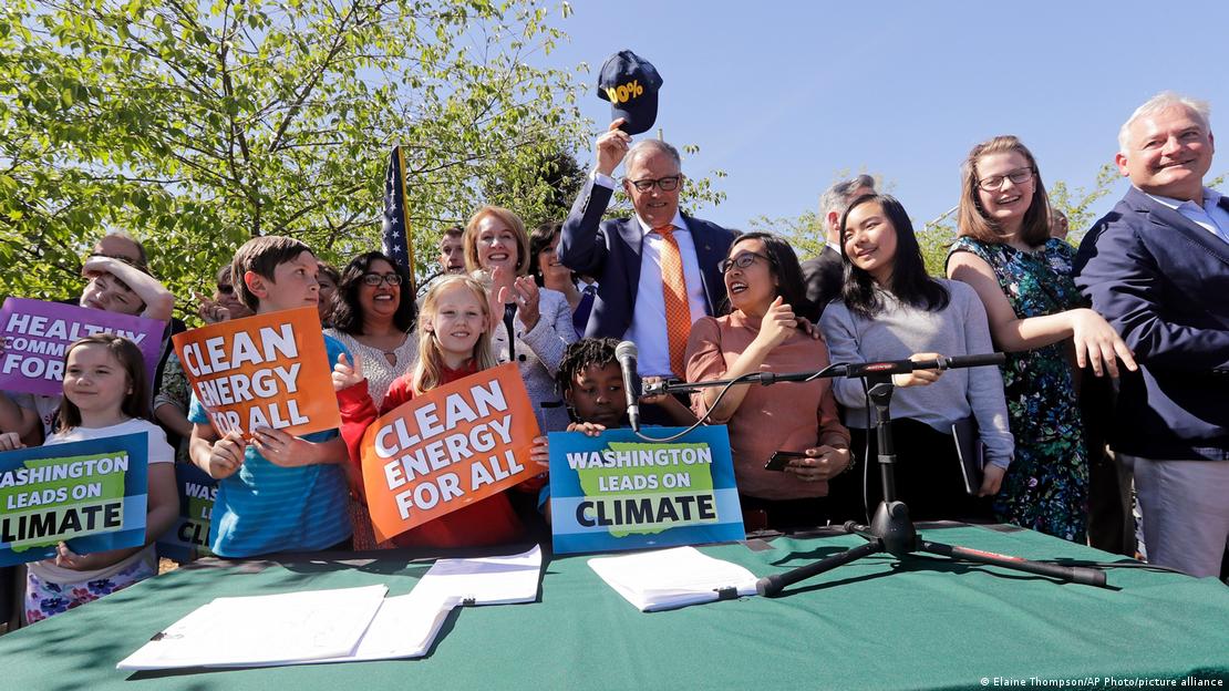 Jay Inslee (Mitte) posiert für eine Foto der Unterzeichnung eines Klimaschutzgesetzes mit Unterstützern, die Schilder mit Slogans für saubere Energie in den Händen halten