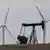 Oil derricks and wind mills are juxtaposed in a field