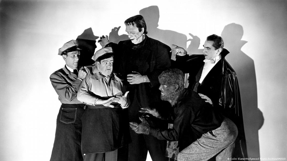 Film still from 'Abbott and Costello Meet Frankenstein': actors posing together, two of them wearing a delivery man's hat, the others dressed a the Frankenstein monster, Dracula and a werewolf.