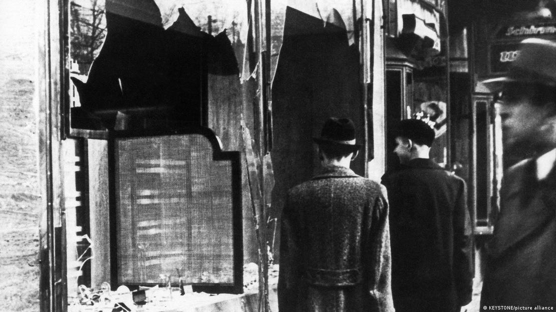 Passersby look at the smashed windows of a Jewish business on November 11, 1938