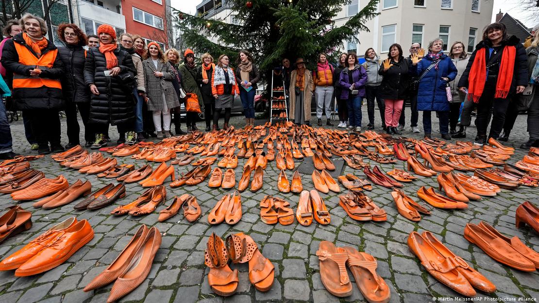 很多双橙色的鞋展示在地上,后面站着一圈妇女 很多双橙色的鞋展示在地上,后面站着一圈妇女