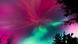Grüne und pinke Polarlichter erhellen den Nachthimmel; an den Bildrändern sind die Umrisse von Baumkronen zu sehen. Grüne und pinke Polarlichter erhellen den Nachthimmel; an den Bildrändern sind die Umrisse von Baumkronen zu sehen.