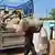 Men unload large sacks of sesame seeds off the bed of a truck in Sudan 