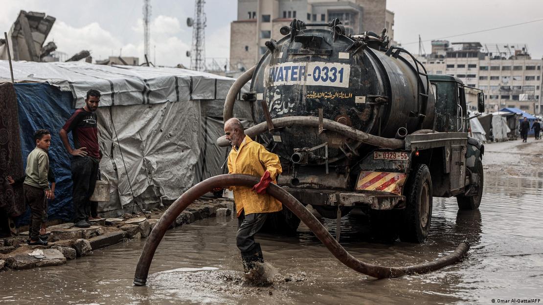 فلسطینی شہری پناہ گزین کیمپ کے قریب بارش کا پانی صاف کر رہا ہے۔