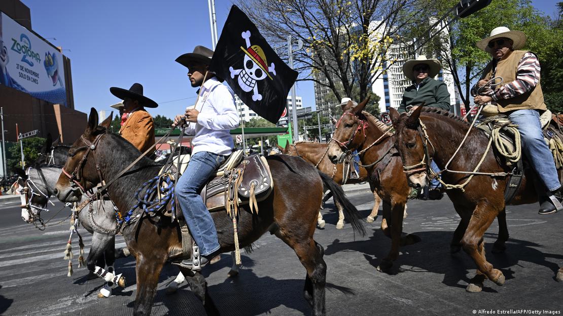 Meksiko'daki gösteride atların üzerinde göstericiler, bir göstericinin elinde One Piece bayrağı görülüyor