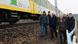 Der polnische Ministerpräsident Donald Tusk und Innenminister Marcin Kierwinski und weitere Männer gehen neben einem stehenden Zug ein Gleisbett entlang, das mit blau-weiße, Flatterband abgesperrt ist