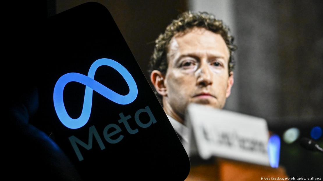 Arka planda Facebook'un kurucusu Mark Zuckerberg yer alırken, ön planda ise onun yönetimindeki sosyal medya çatı şirketi Meta'nın logosunun yer aldığı bir akıllı telefon ekranı bulunuyor 