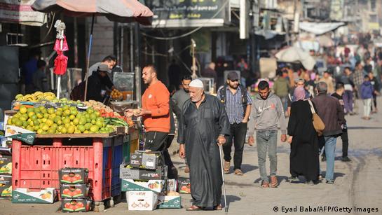 Palestinos caminham por uma rua comercial em Deir al-Balah, na região central da Faixa de Gaza.
