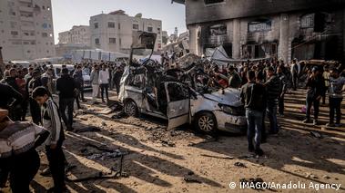 Συγκεντρωμένο πλήθος γύρω από ένα κατεστραμμένο αυτοκίνητο 