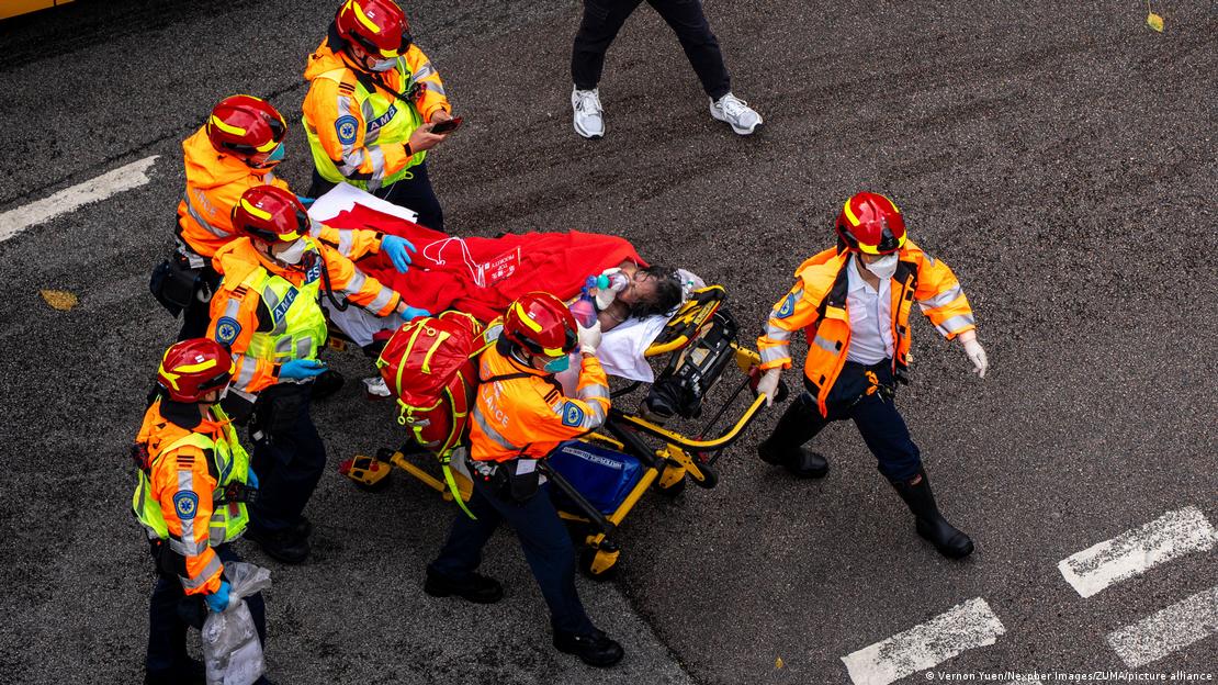 Equipes levando pessoa em uma maca atravessa a rua