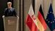 Krzysztof Gawkowski przemawia na mównicy w ambasadzie w Berlinie, z boku flagi: Polski, Niemiec i UE Krzysztof Gawkowski przemawia na mównicy w ambasadzie w Berlinie, z boku flagi: Polski, Niemiec i UE