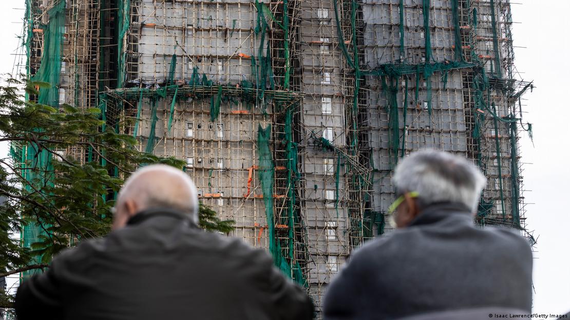 Dos personas miran los edificios destruidos por las llamas en el complejo de viviendas de varias torres Wang Fuk Court, en el distrito de Tai Po, Hong Kong.
