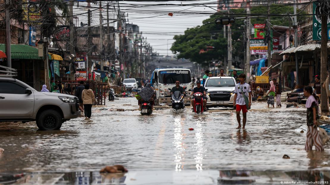 Motos, carros e pedestres em rua alagada de Hat Yai, na Tailândia