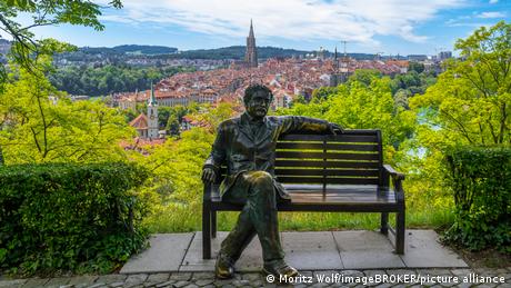 Eine Bank mit der Statue eines Manns, dahinter eine Stadt (Quelle: Moritz Wolf/imageBROKER/picture alliance)