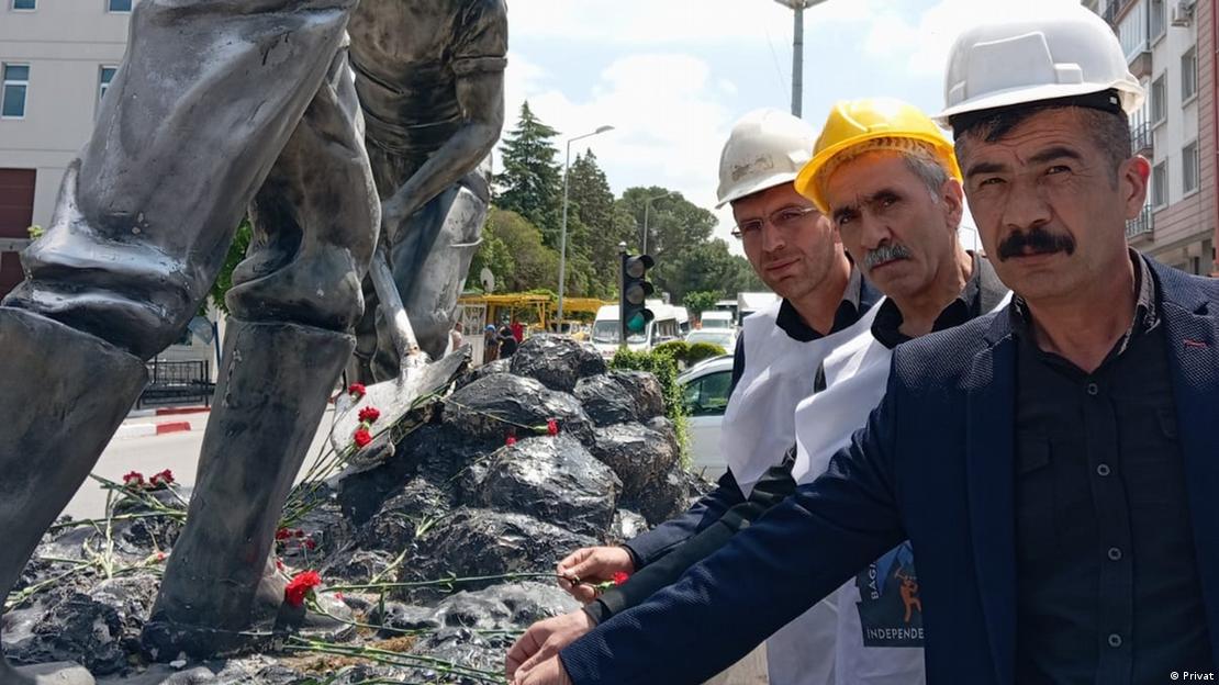 Bağımsız Maden-İş Sendikası Genel Başkanı Gökay Çakır, iki meslektaşı ile madenciler anısına yapılmış bir anıta çiçek bırakırken 
