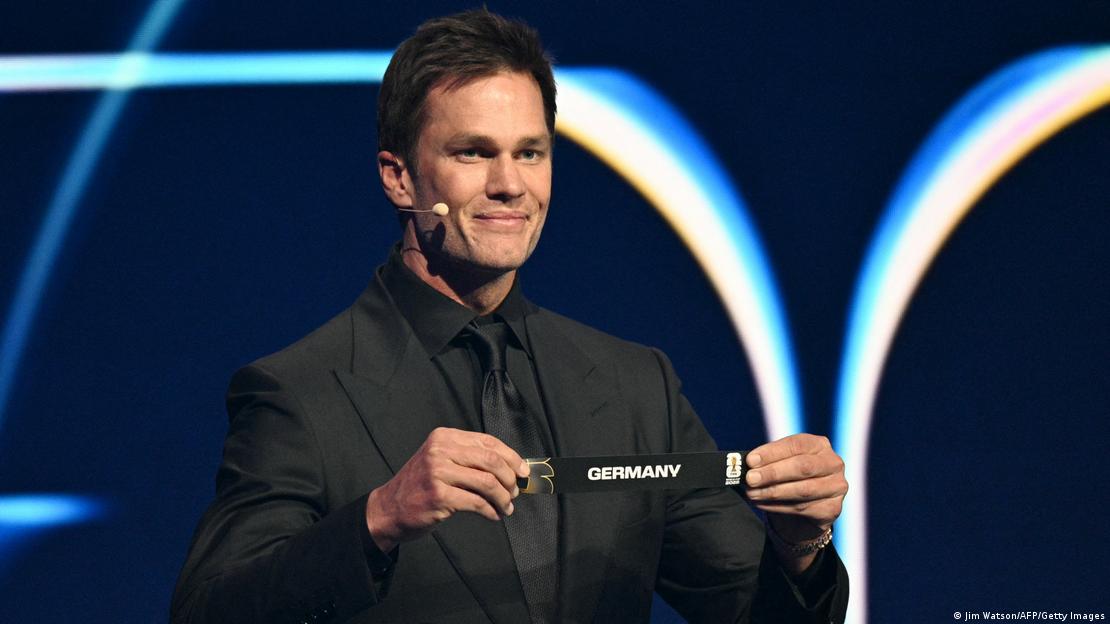 El futbolista estadounidense Tom Brady muestra el nombre de Alemania durante el sorteo.