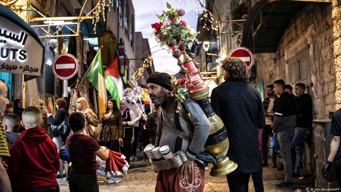 اسرائیل کے مقبوضہ مغربی کنارے میں بیت لحم میں کرسمس ٹری لائٹنگ کی تقریب کے دوران ایک شخص نیٹیویٹی اسکوائر میں کافی بیچ رہا ہے