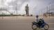 A motorist drives his motorbike past the Amazone statue in Cotonou A motorist drives his motorbike past the Amazone statue in Cotonou