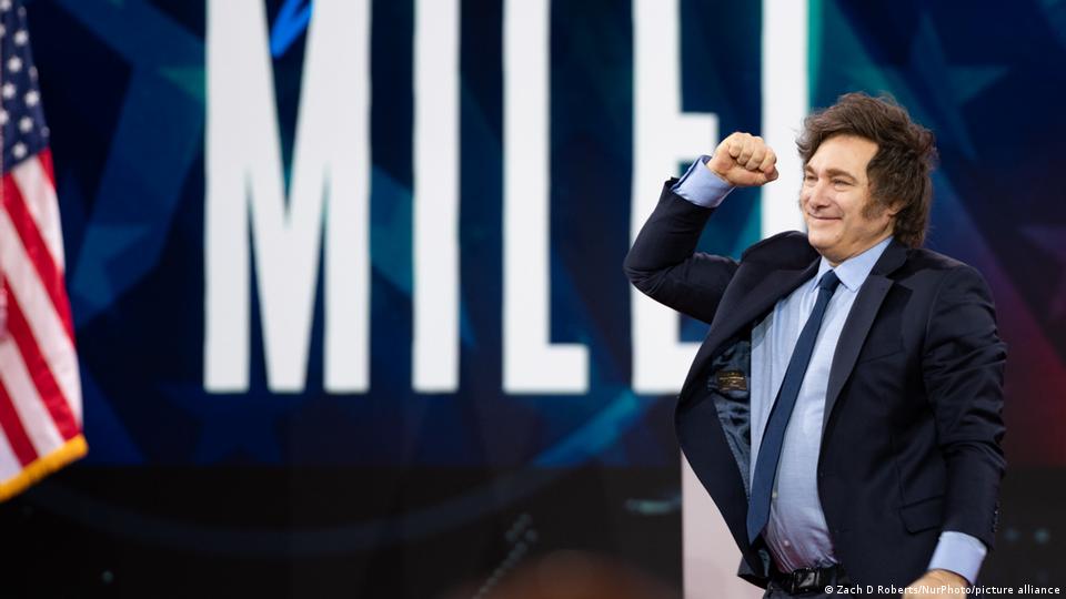 Javier Milei alza el puño junto a una bandera de EE. UU. Javier Milei alza el puño junto a una bandera de EE. UU.