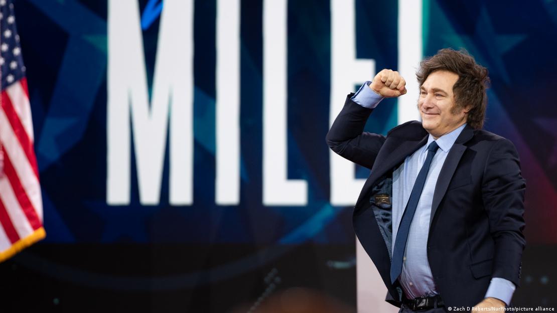 Javier Milei alza el puño junto a una bandera de EE. UU.