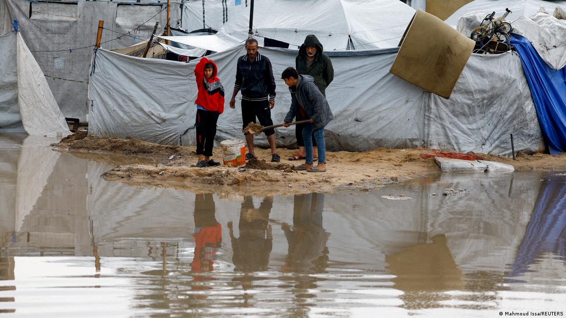 Palestinos en medio de inundaciones y tiendas de campaña destruidas por el agua en Gaza.