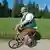 An overweight man dressed in traditional Bavarian costume rides a tiny bicycle.