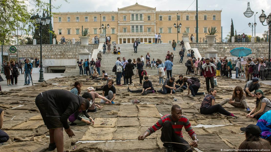 Οι άνθρωποι ράβουν μαζί σάκοι με κάρβουνο σε μια πλατεία ως μέρος μιας εγκατάστασης από τον Ibrahim Mahama.