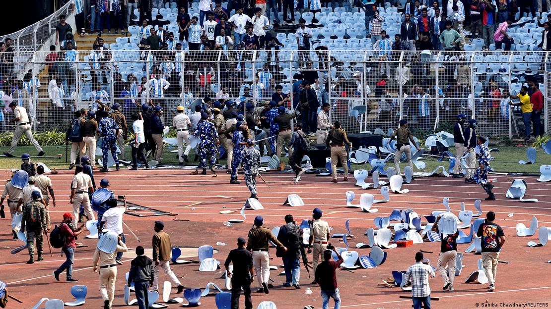 Multitud de asientos sobre el campo de fútbol y la pista de atletismo circundante, con personal de seguridad y prensa en el campo. Multitud de asientos sobre el campo de fútbol y la pista de atletismo circundante, con personal de seguridad y prensa en el campo.