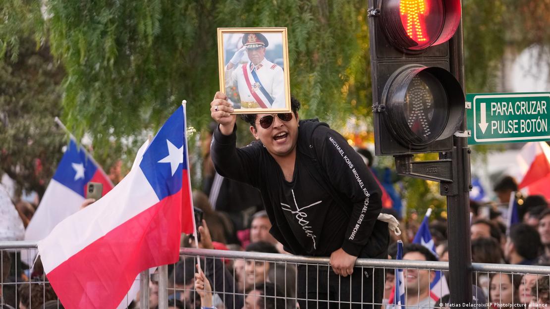 Un partidario de José Antonio Kast, subido sobre una valla, sostiene un retrato del exdictador militar general Augusto Pinochet durante la celebración en Santiago, tras la segunda vuelta de las elecciones presidenciales. (14.12.2025)