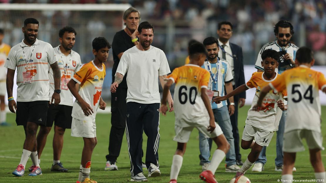 El futbolista argentino Lionel Messi observa mientras jóvenes aficionados juegan al fútbol en el estadio Wankhede de Bombay