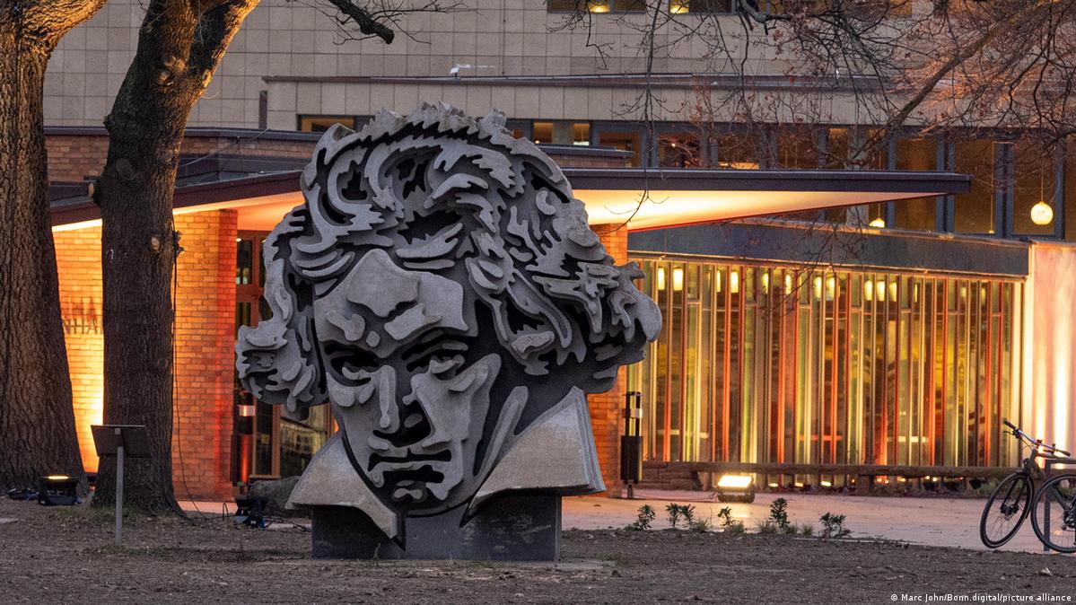 Beethoven monument in the forecourt of the illuminated Beethovenhalle in Bonn.