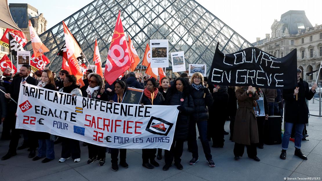 Funcionários carregam placas e bandeiras durante greve na frente do Museu do Louvre Funcionários carregam placas e bandeiras durante greve na frente do Museu do Louvre