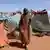 A Sudanese displaced woman who was held by the paramilitary Rapid Support Forces (RSF), carries a water container