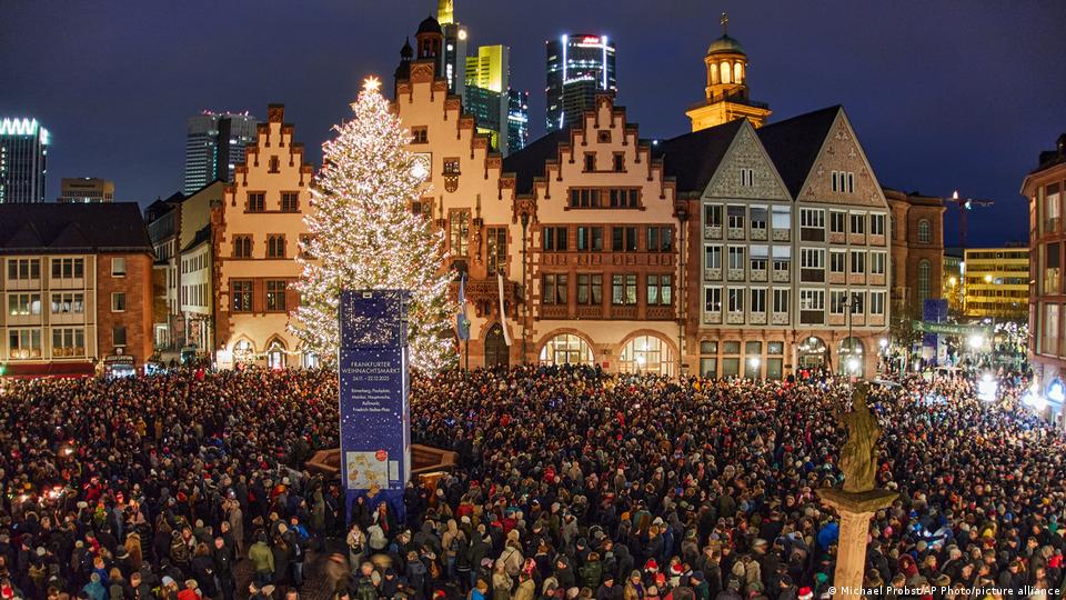 People gather in Roemerberg square, with a large Christmas tree lit up in the background on Dec 24, 2025