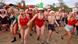 People in bathing suits yell as they hold hands and get ready to run