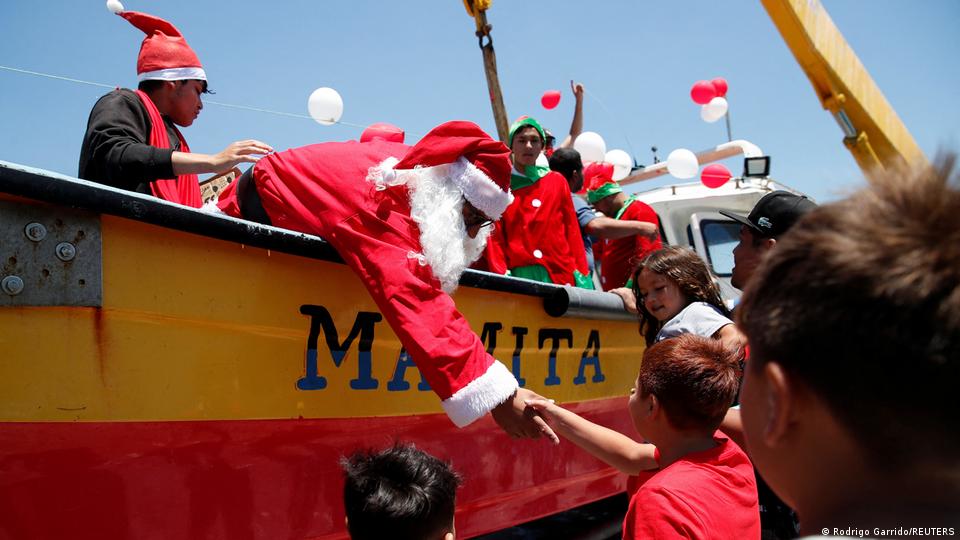 A man dressed as Santa Clause standing in a fishing boat shakes hands with a child on Dec 24, 2025